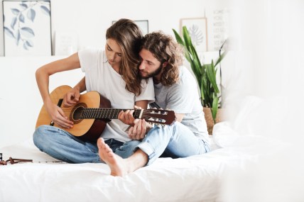 Loving couple indoors at home play on guitar.